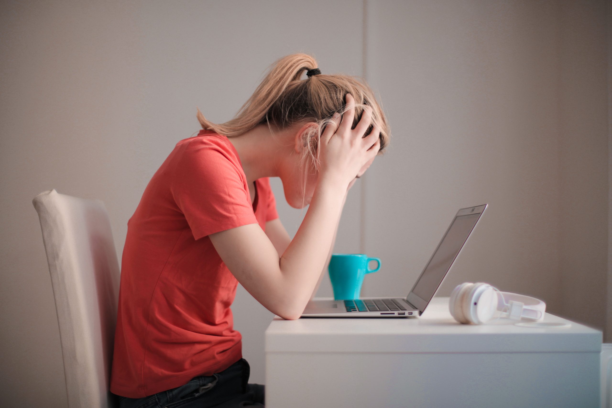 Stressed college student holding her head while studying at a laptop, illustrating AI detection anxiety